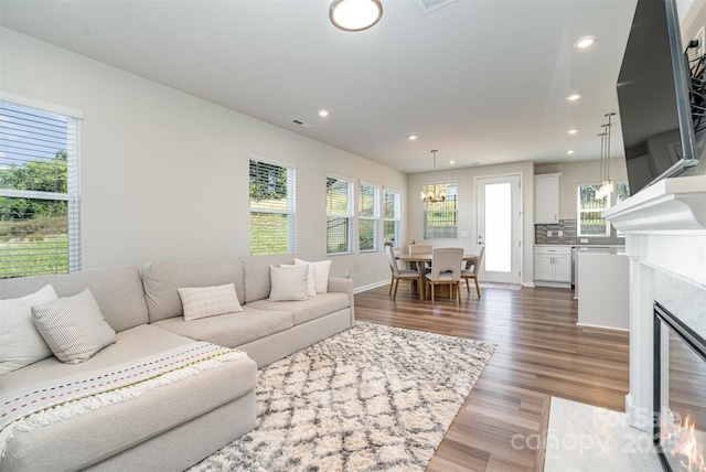 living room with a chandelier, a high end fireplace, plenty of natural light, and wood-type flooring