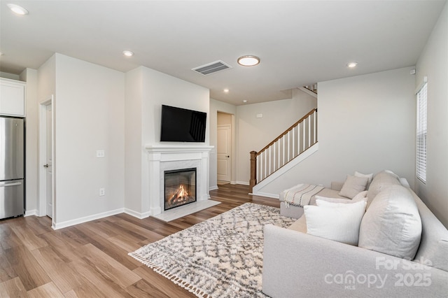 living room with a high end fireplace, a wealth of natural light, and light hardwood / wood-style flooring