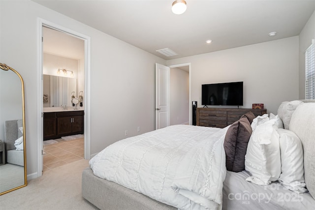 bedroom featuring ensuite bathroom and light carpet