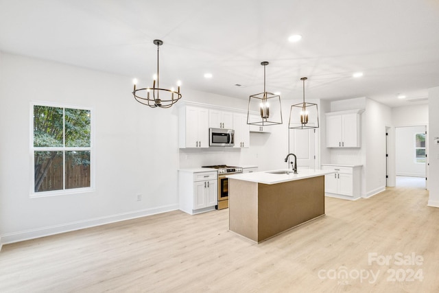 kitchen with white cabinets, sink, a kitchen island with sink, decorative light fixtures, and stainless steel appliances