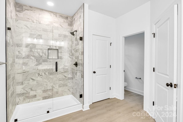 bathroom featuring wood-type flooring, walk in shower, and toilet