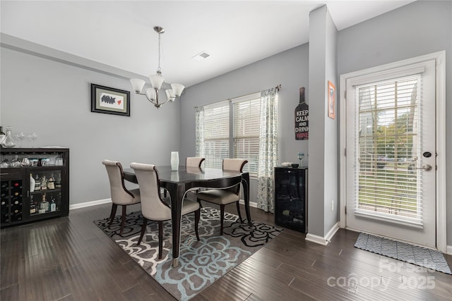 dining room featuring a wealth of natural light, dark wood finished floors, baseboards, and an inviting chandelier