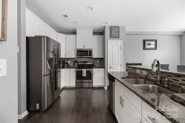 kitchen featuring stainless steel appliances, dark stone counters, visible vents, and a sink