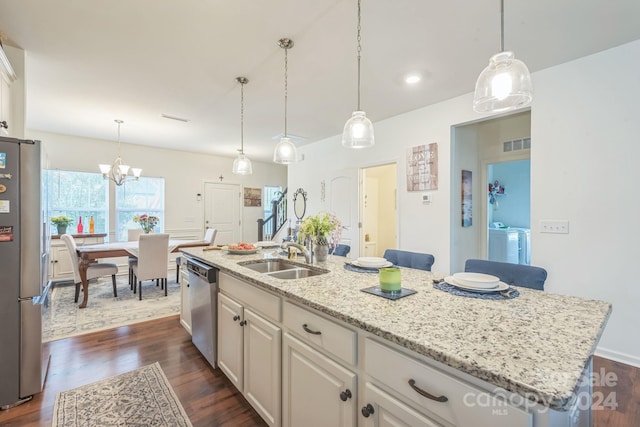 kitchen with appliances with stainless steel finishes, dark hardwood / wood-style flooring, a center island with sink, and sink