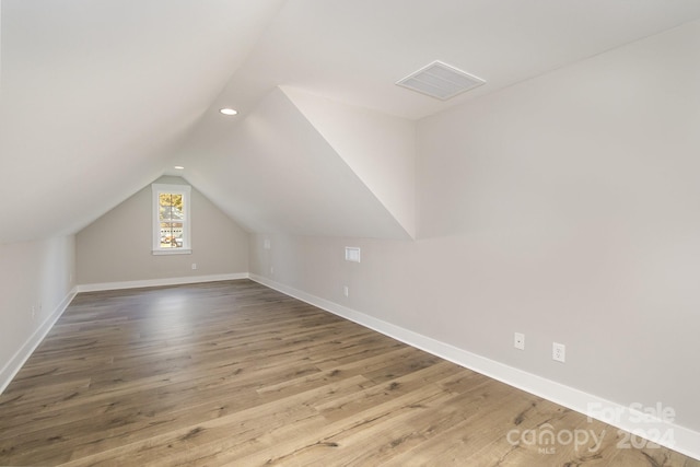 additional living space with vaulted ceiling and hardwood / wood-style flooring