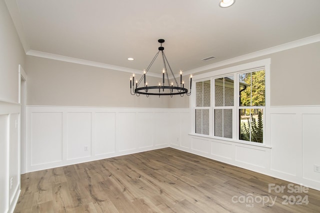 unfurnished dining area featuring crown molding, a notable chandelier, and wood-type flooring