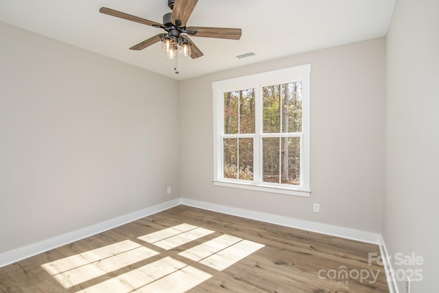 spare room with baseboards, wood finished floors, and a ceiling fan