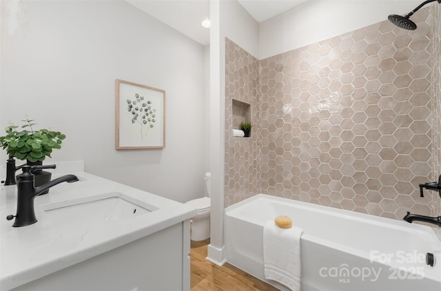 full bath featuring wood finished floors, a sink, toilet, and  shower combination