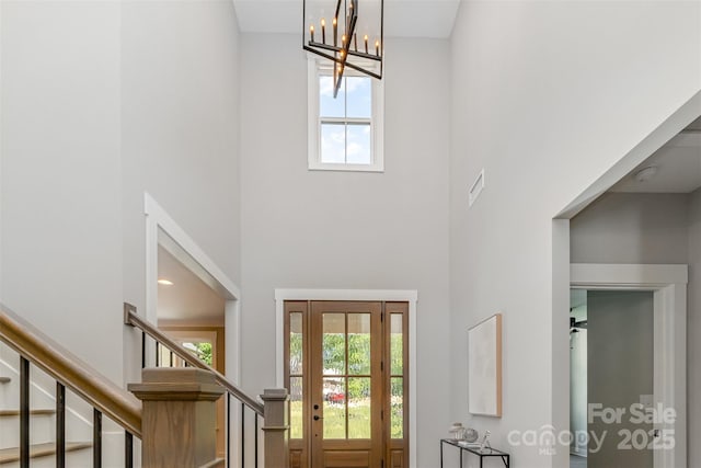 entrance foyer with a towering ceiling, a chandelier, and stairs