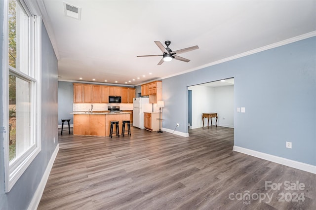 kitchen with white fridge, crown molding, dark hardwood / wood-style flooring, a breakfast bar, and stainless steel range oven