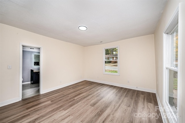 unfurnished room featuring hardwood / wood-style flooring and a textured ceiling