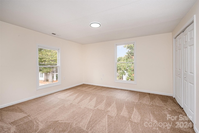 unfurnished bedroom with a closet, multiple windows, and carpet flooring