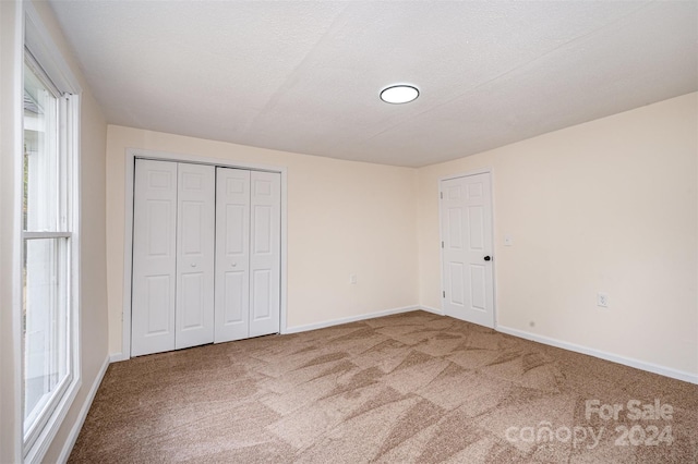 unfurnished bedroom with multiple windows, a closet, and carpet