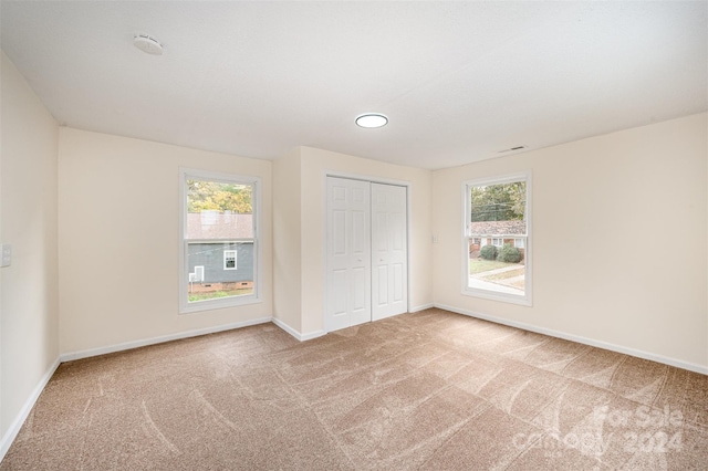 unfurnished bedroom with multiple windows, carpet flooring, and a closet