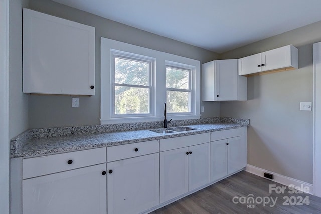 kitchen featuring white cabinetry, light stone countertops, sink, and dark wood-type flooring