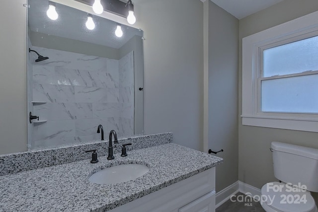 bathroom with vanity, tiled shower, and toilet