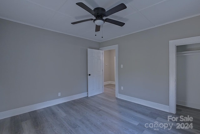 unfurnished bedroom with crown molding, hardwood / wood-style flooring, a closet, and ceiling fan