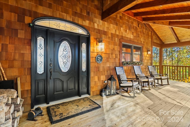 foyer with vaulted ceiling with beams, wood walls, hardwood / wood-style floors, and a healthy amount of sunlight