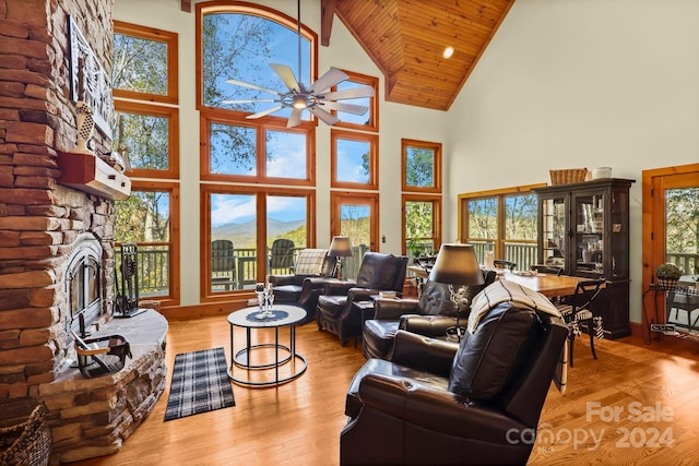 living room with light hardwood / wood-style flooring, high vaulted ceiling, a fireplace, and ceiling fan