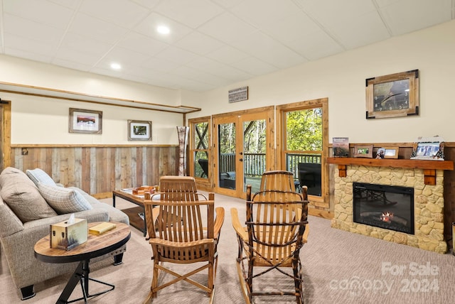 carpeted living room featuring french doors, a fireplace, and wood walls