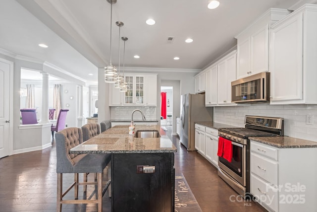 kitchen featuring sink, white cabinetry, dark stone countertops, appliances with stainless steel finishes, and a kitchen island with sink