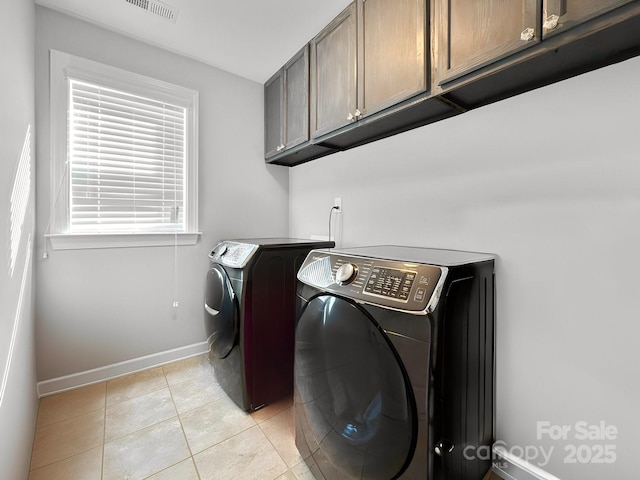 clothes washing area featuring cabinets, washer and dryer, and light tile patterned floors