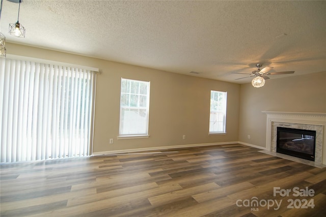 unfurnished living room with hardwood / wood-style flooring, a high end fireplace, ceiling fan, and a textured ceiling