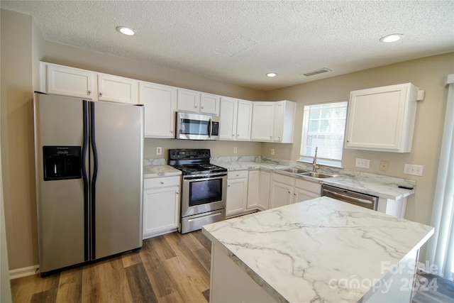 kitchen featuring white cabinets, sink, a textured ceiling, hardwood / wood-style flooring, and appliances with stainless steel finishes