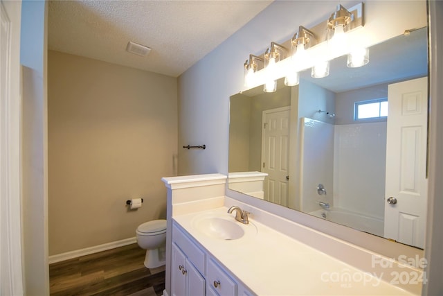 full bathroom with tub / shower combination, vanity, hardwood / wood-style flooring, toilet, and a textured ceiling