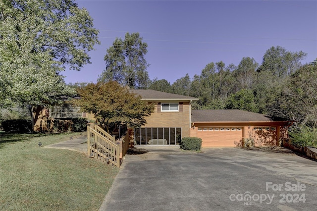 view of front of property featuring a front yard, a garage, and a sunroom