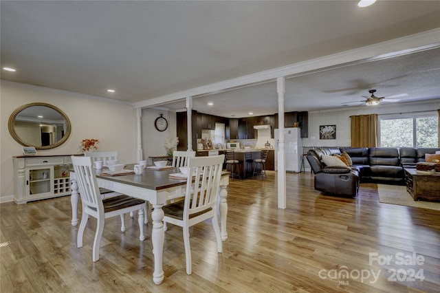 dining area with a textured ceiling, light wood-type flooring, and ceiling fan