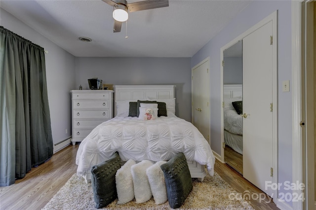 bedroom with a baseboard radiator, ceiling fan, a textured ceiling, and light hardwood / wood-style flooring