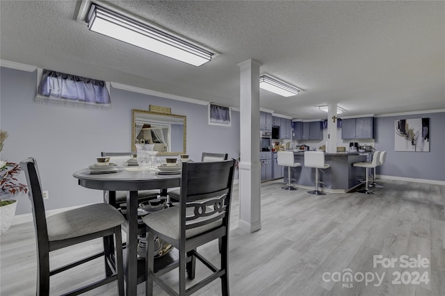 dining area featuring light hardwood / wood-style floors, crown molding, and a textured ceiling