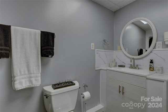 bathroom featuring toilet, vanity, and backsplash