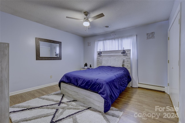 bedroom featuring light hardwood / wood-style floors, a textured ceiling, a baseboard radiator, and ceiling fan