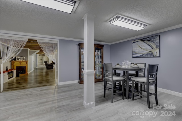 dining area with light hardwood / wood-style flooring, ornamental molding, and a textured ceiling