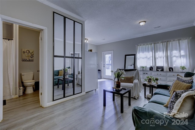 living room featuring ornamental molding, a textured ceiling, and light hardwood / wood-style floors