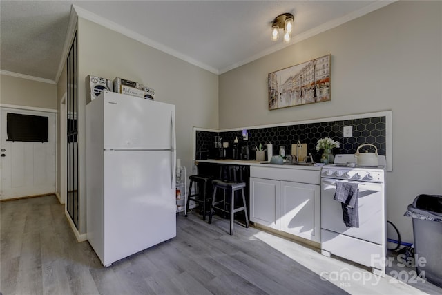 kitchen featuring white appliances, light hardwood / wood-style floors, crown molding, and tasteful backsplash