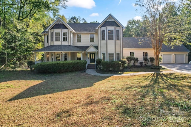 victorian-style house featuring a garage, a porch, and a front yard