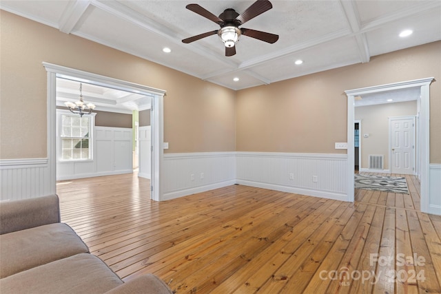 unfurnished living room featuring ceiling fan with notable chandelier, crown molding, coffered ceiling, and light hardwood / wood-style flooring