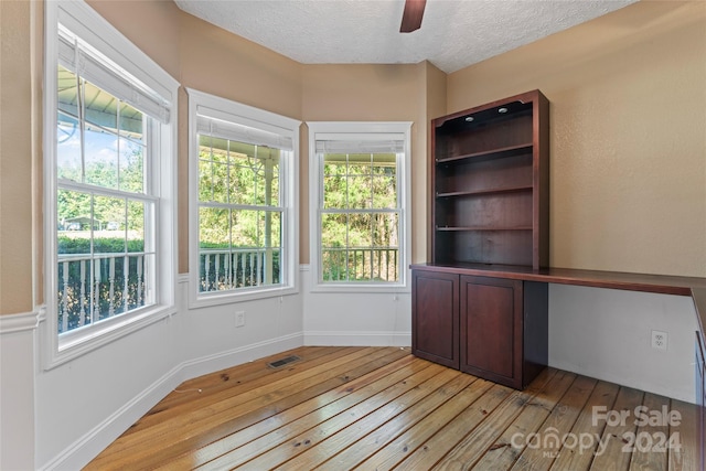 unfurnished office featuring ceiling fan, a textured ceiling, and light hardwood / wood-style flooring