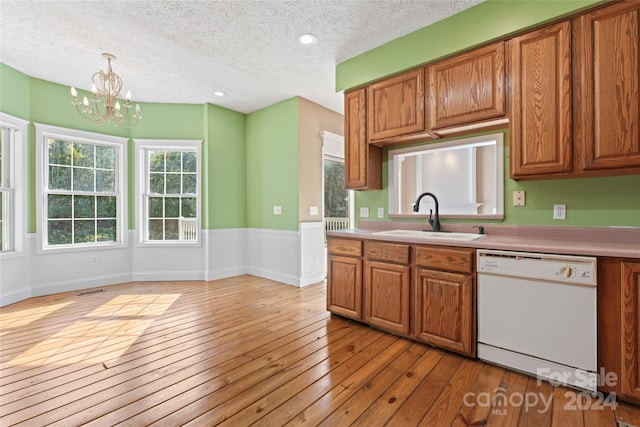 kitchen featuring sink, decorative light fixtures, dishwasher, an inviting chandelier, and light wood-type flooring