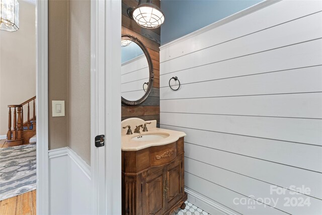 bathroom featuring hardwood / wood-style flooring, wood walls, and vanity