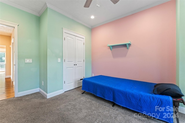 bedroom featuring a closet, crown molding, carpet flooring, and ceiling fan