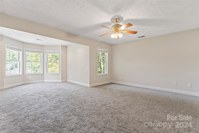 spare room with ceiling fan, a textured ceiling, carpet flooring, and a healthy amount of sunlight