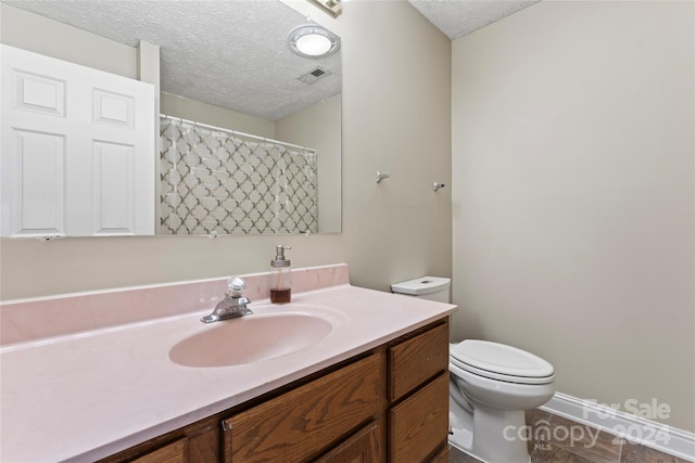 bathroom featuring vanity, toilet, and a textured ceiling