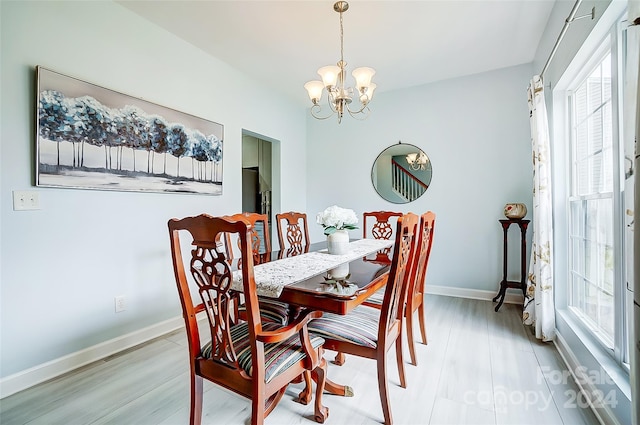 dining space featuring light wood-type flooring, an inviting chandelier, and plenty of natural light