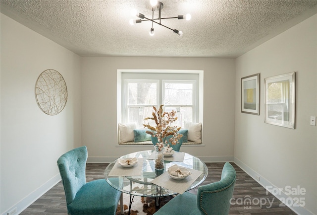 dining space featuring a textured ceiling, baseboards, dark wood-style flooring, and a chandelier