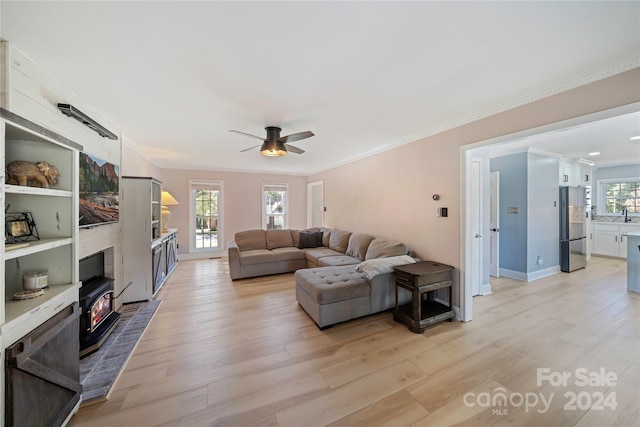 living room with crown molding, light hardwood / wood-style flooring, and ceiling fan