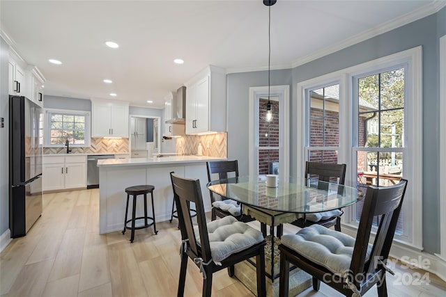 dining space featuring crown molding, light hardwood / wood-style flooring, and sink